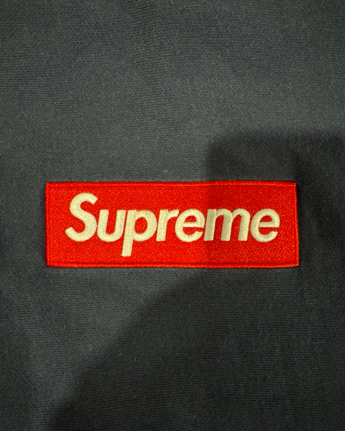 Dark hoodie fabric with red Supreme logo patch