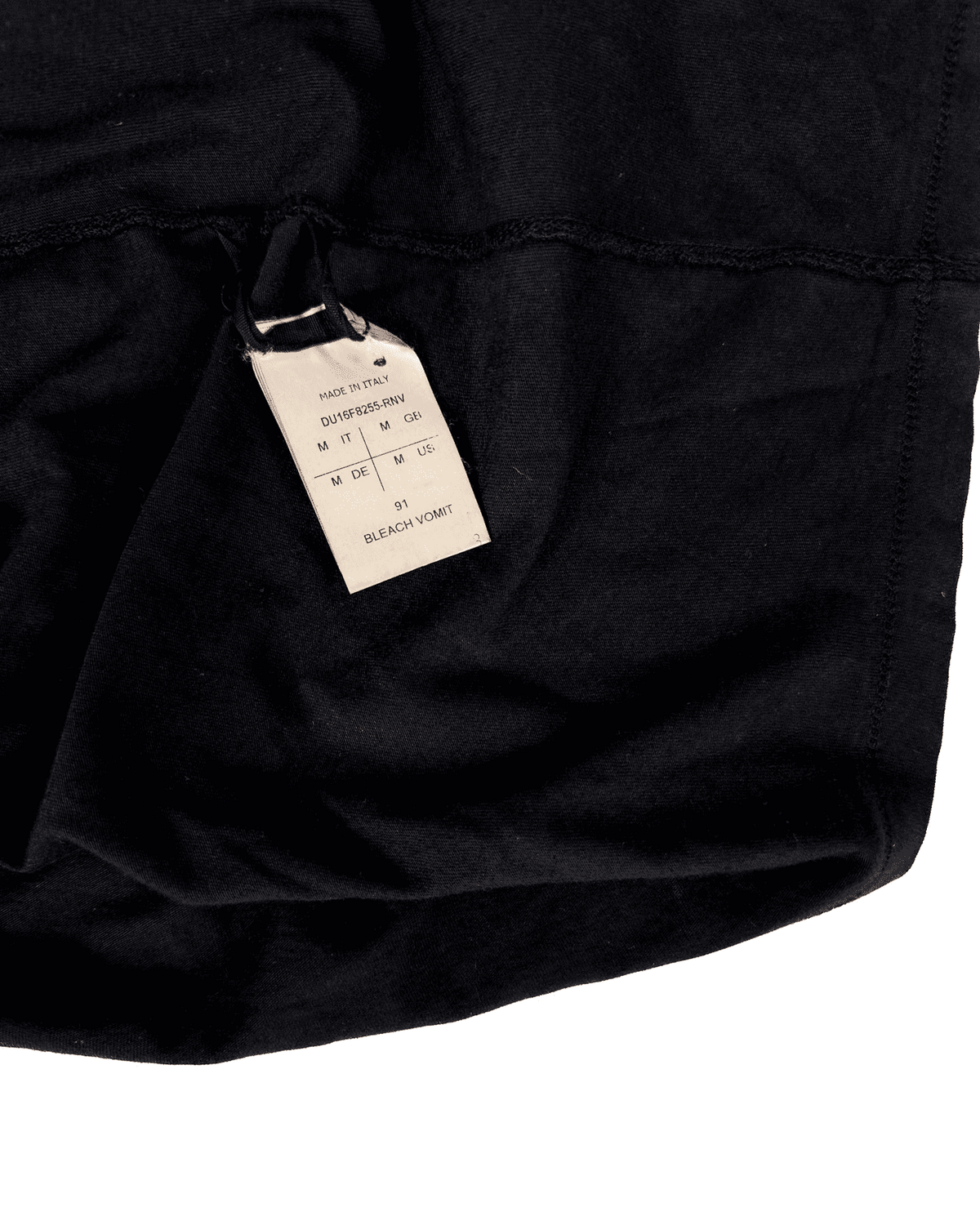 Black T-shirt with fabric drape and size/brand neck label close-up