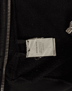 Dark hoodie interior showing size/brand label near hem and zipper area