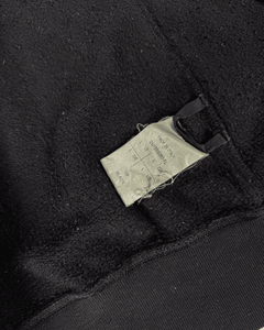 Dark hoodie fabric close-up with woven care label and ribbed cuff hem