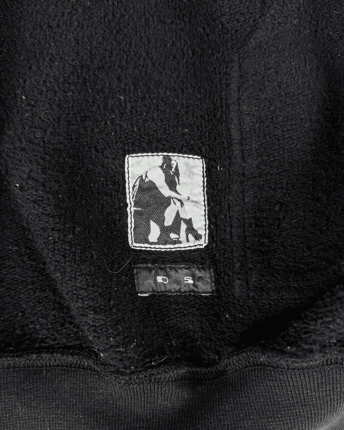Dark hoodie chest patch with small horse graphic and outerwear label details