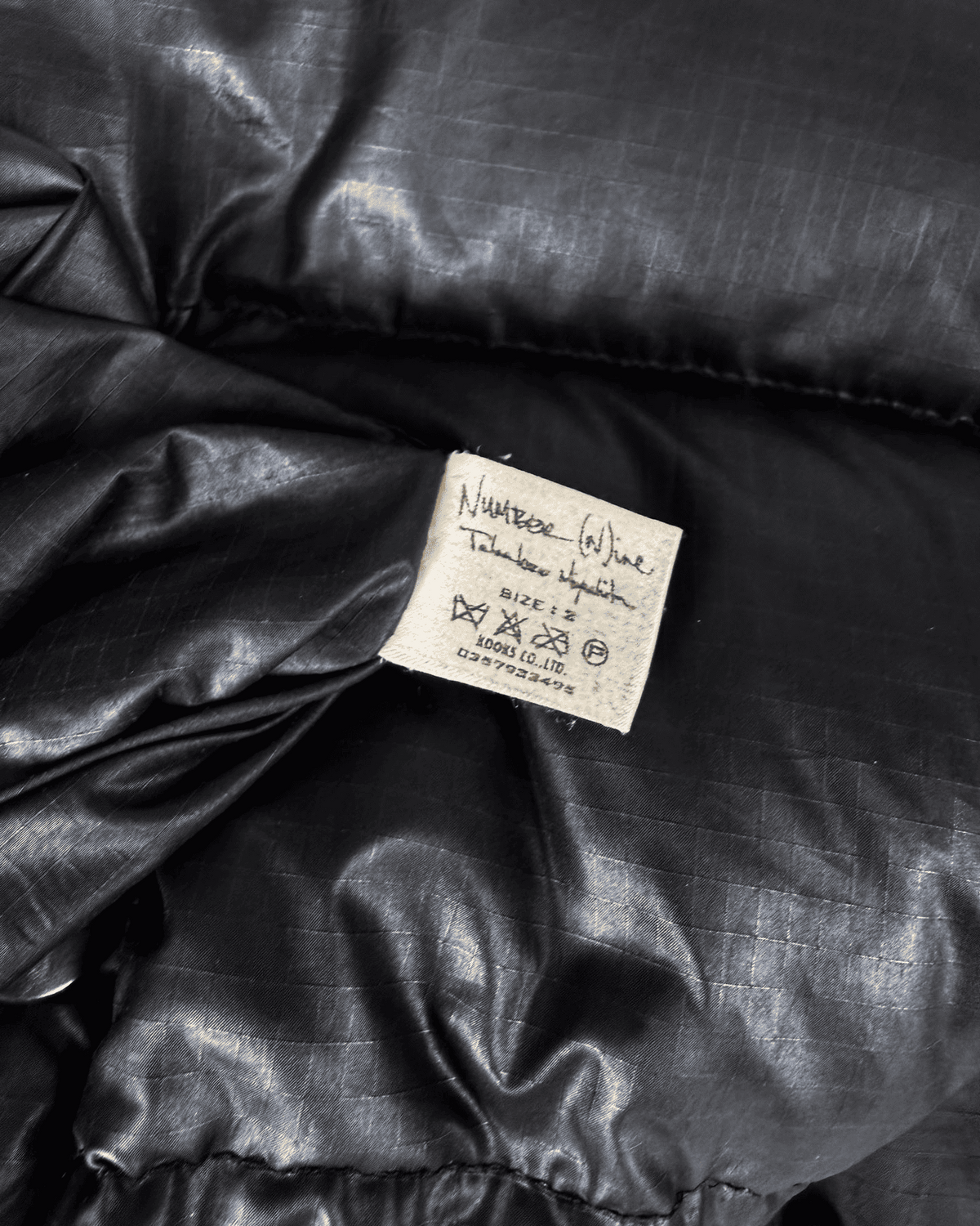 Black puffer vest fabric label with size and care details