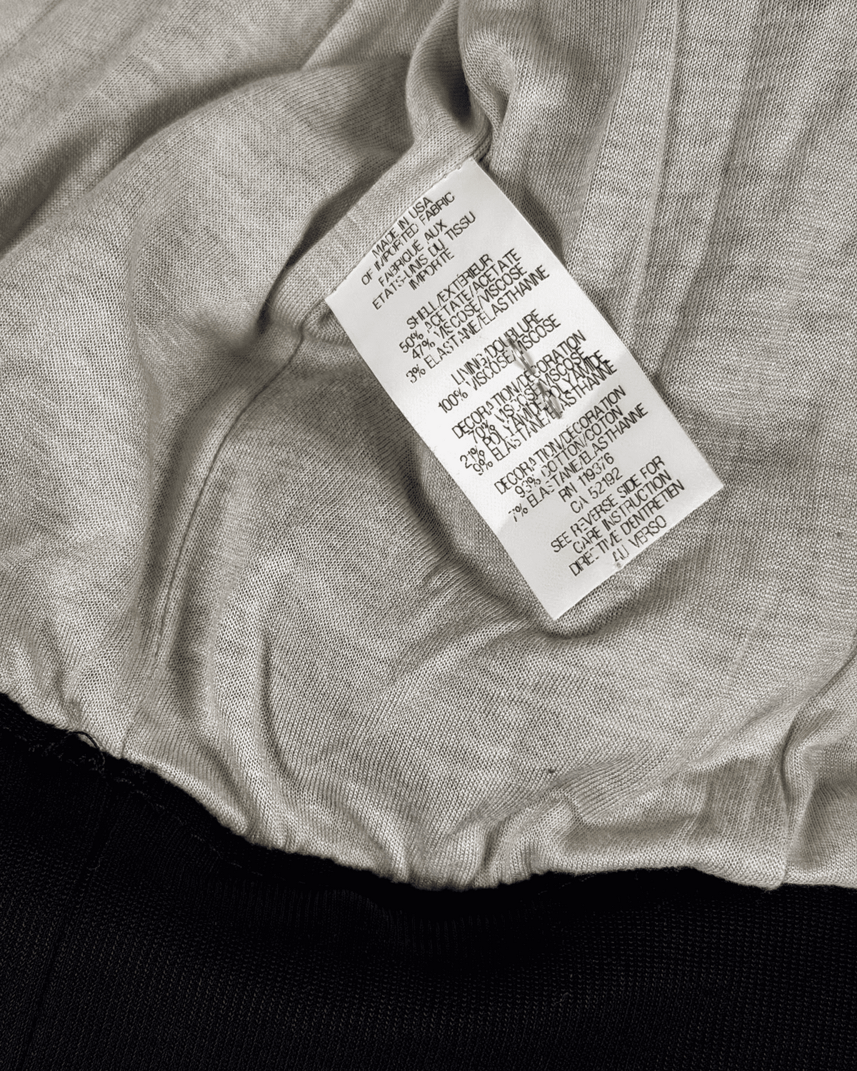 Interior care label tag on light-beige bomber, ribbed black hem and cuffs
