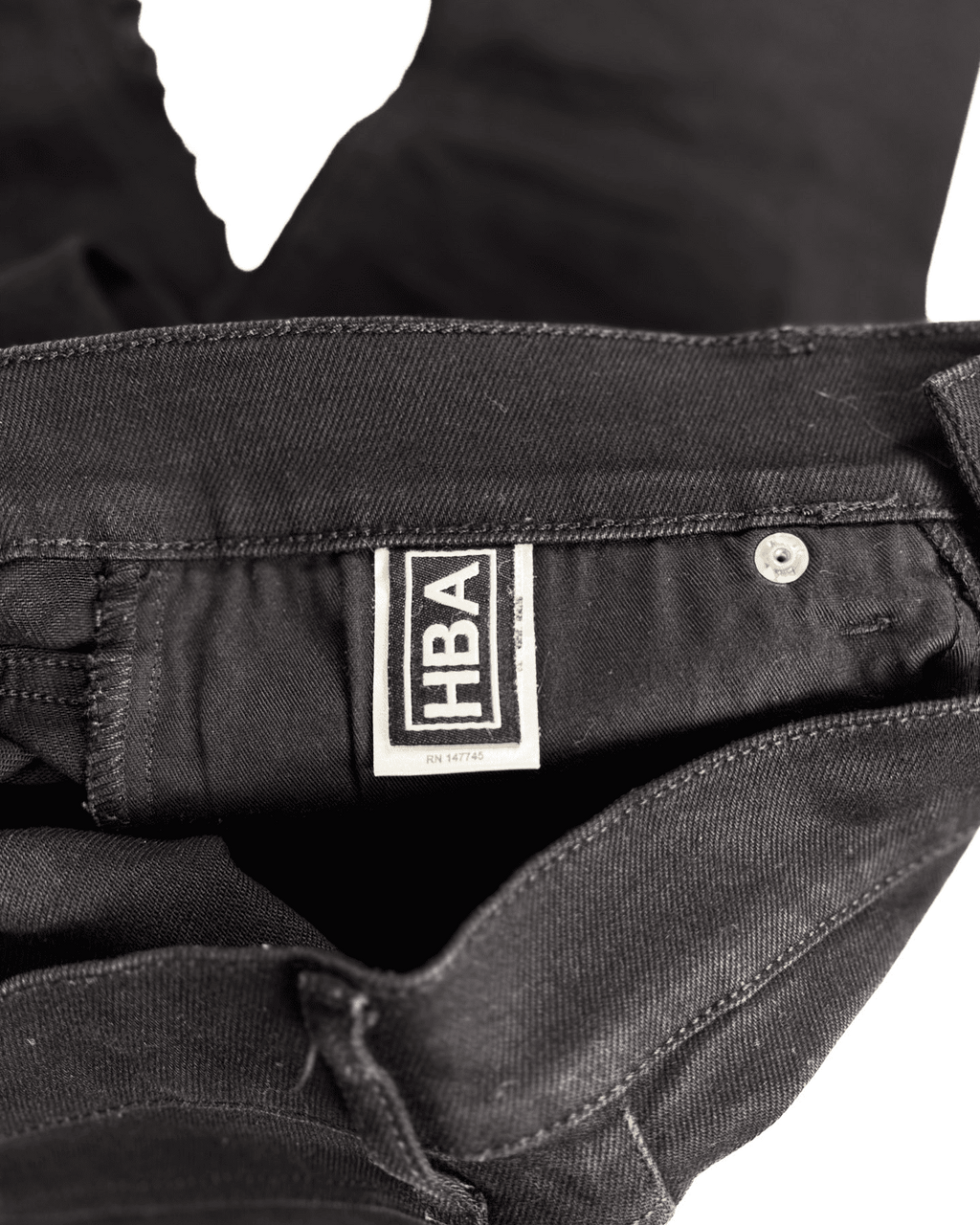 Distressed black denim jeans with HBA label at waistband and metal button
