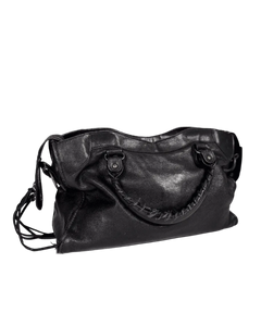 Black leather shoulder bag with curved top, front zipper, and side buckle strap tabs