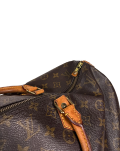 Louis Vuitton duffle bag close-up of tan leather tab and gold zipper hardware