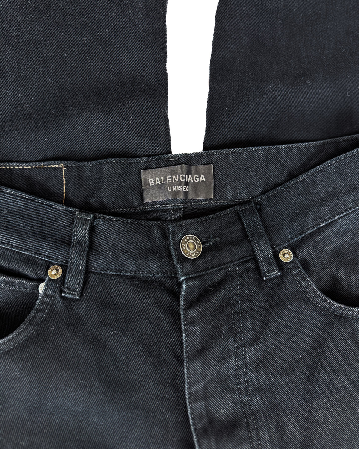 Black denim jeans waist with Balenciaga logo label and gold button.