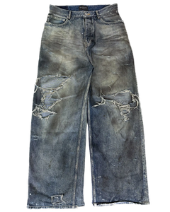 Distressed blue denim jeans with oil-splatter wash and large ripped patches