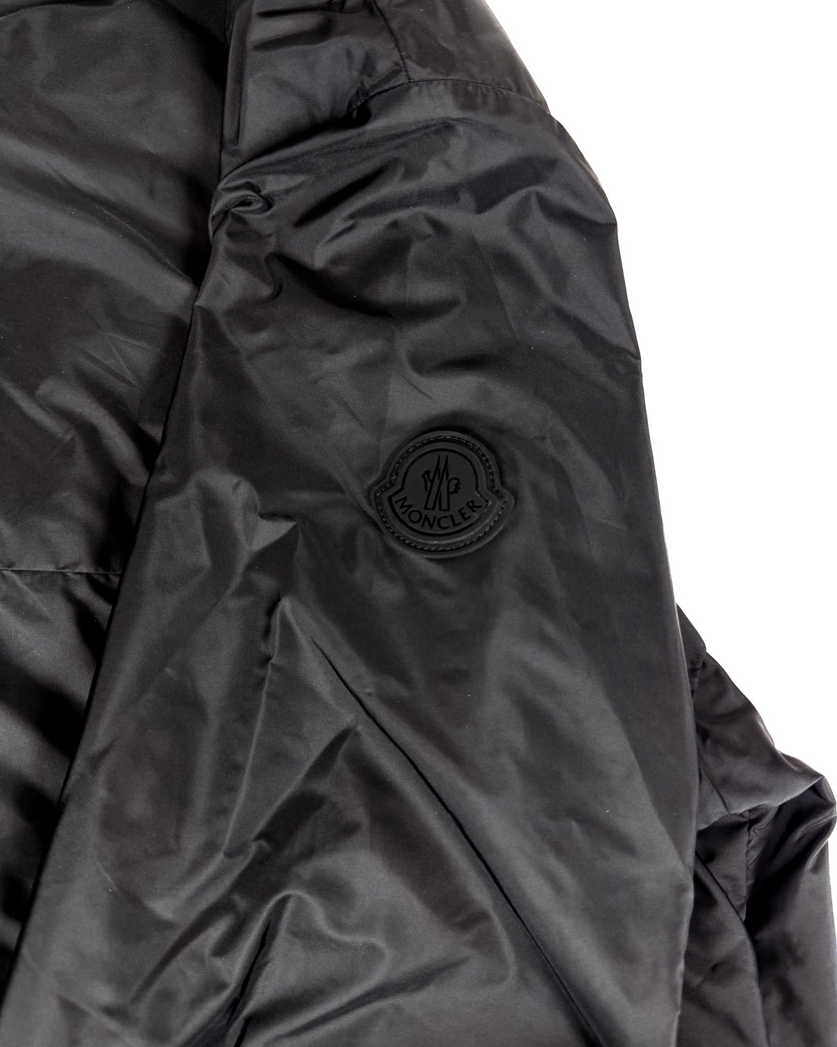 Moncler logo patch on dark black jacket sleeve, round emblem badge