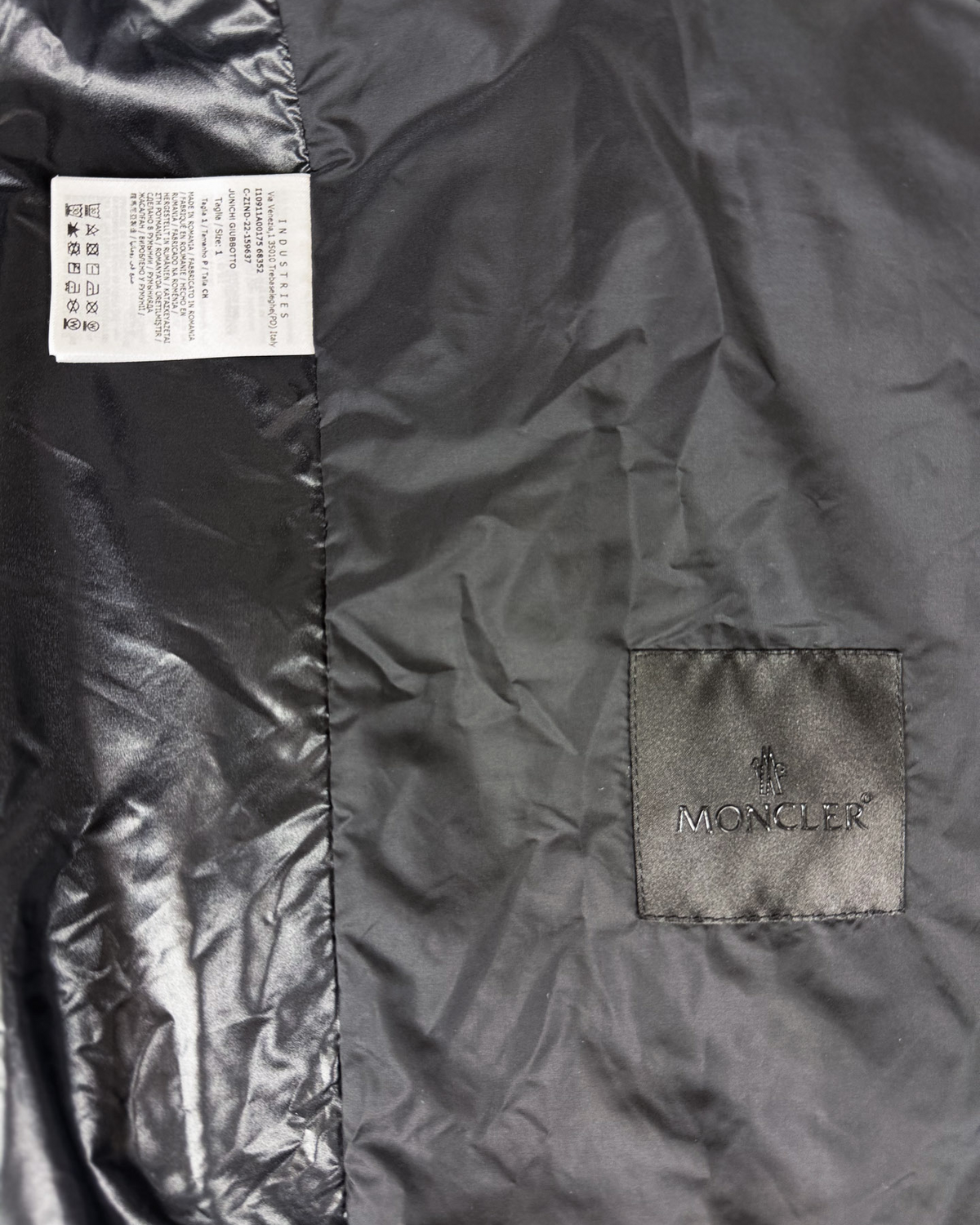 Moncler logo patch and size label on dark black jacket fabric panel