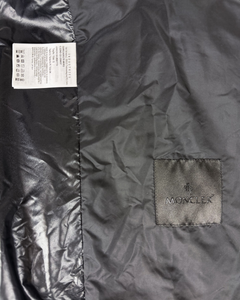 Moncler logo patch and size label on dark black jacket fabric panel