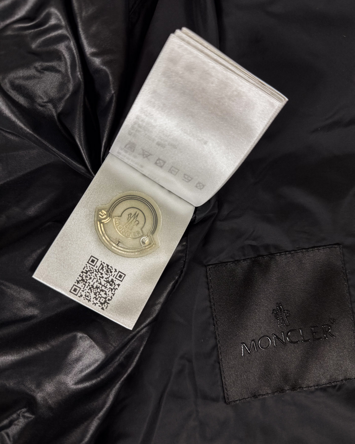 Moncler logo patch and care tag on dark black jacket fabric