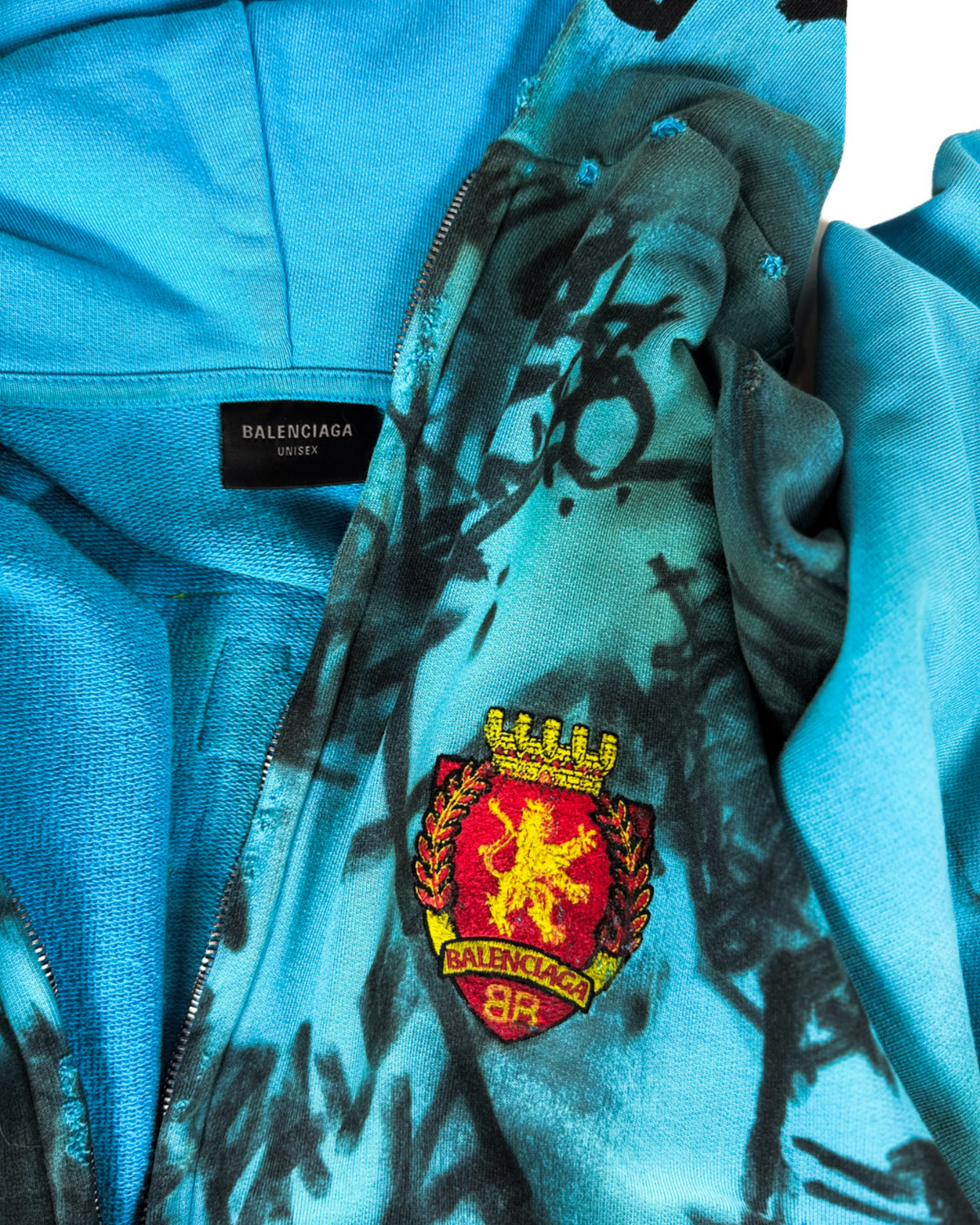 Blue zip-up hoodie inner view with Balenciaga-universe label and crest patch
