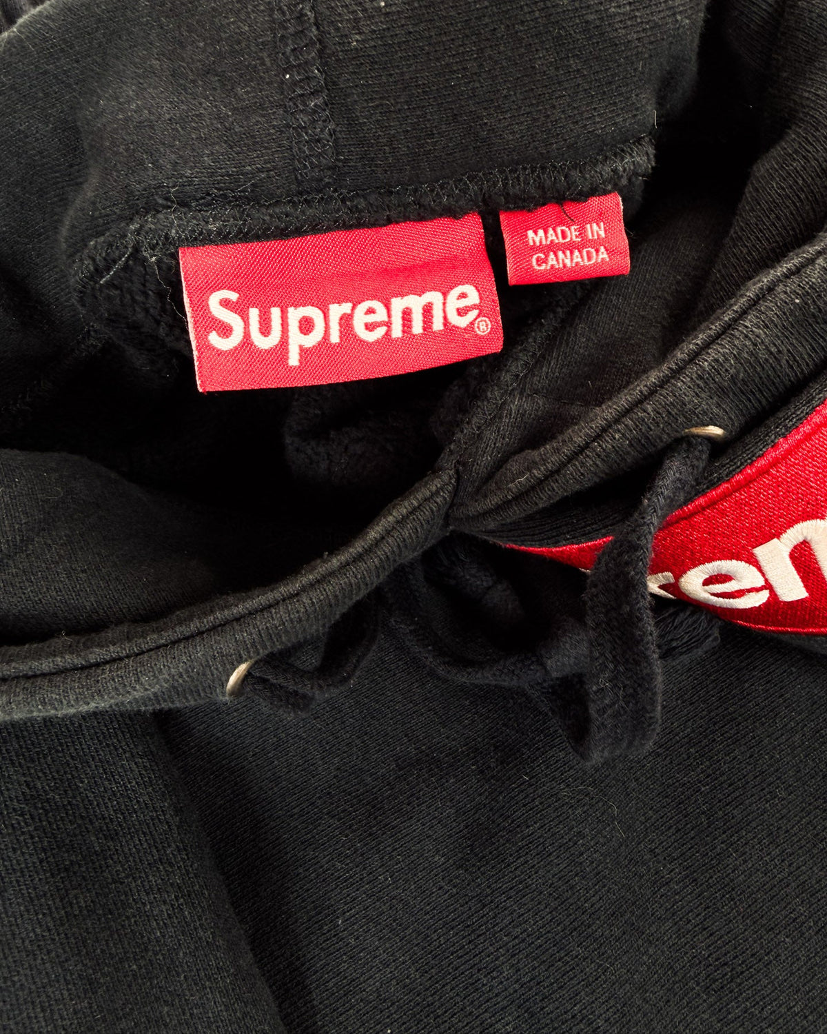 Black hoodie neckline with Supreme label and red Made in Canada tag